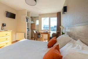 a bedroom with a bed and a table and a window at Residence Des Thermes in Lons-le-Saunier