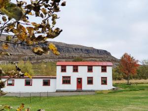 una casa bianca con una porta rossa di fronte a una montagna di Fossardalur Guesthouse a Djúpivogur