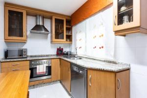 uma cozinha com armários de madeira e um forno com placa de fogão em APARTAMENTO EN A ESTRADA/GALICIA em A Estrada