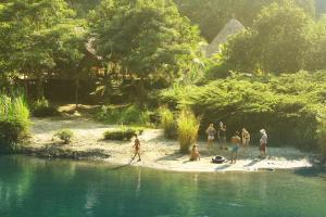 a group of people standing on the shore of a river at Rio Hostel Buritaca in Buritaca