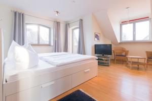 ein weißes Schlafzimmer mit einem großen Bett und einem TV in der Unterkunft Dünenhof DÜNENHOF Whg. D-12 in Wustrow