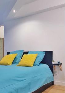 niebieskie łóżko z dwoma żółtymi poduszkami w obiekcie STUDIO ZEN SOBRE CHIC w mieście Bordeaux