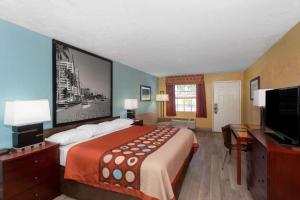 a hotel room with a bed and a flat screen tv at Super 8 by Wyndham Bradenton Sarasota Area in Bradenton