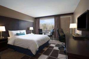 Travelodge by Wyndham Kapuskasing في كابوسكاسينغ: غرفة فندقية بسرير وطاولة وكراسي