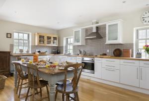 a kitchen with white cabinets and a table with chairs at Claytons Cottage in Adlestrop