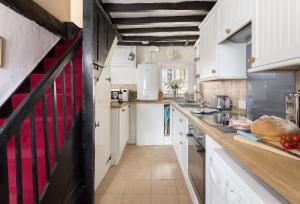 a large kitchen with white cabinets and a red stripe on the counter at Church Cottage in Chipping Norton