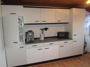 a kitchen with white cabinets and a microwave at FeWo Ahornweg in Selb