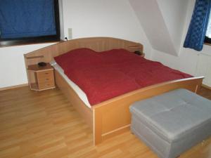 a bedroom with a wooden bed with a red blanket at FeWo Ahornweg in Selb