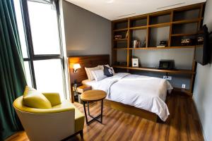 ein Schlafzimmer mit einem Bett, einem Stuhl und einem Fenster in der Unterkunft Hotel The Designers Jongro in Seoul
