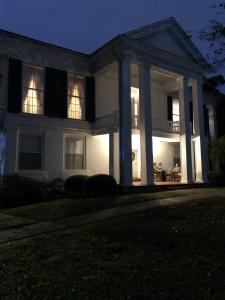 uma grande casa branca com um alpendre à noite em The Montgomery B&B em Starkville