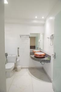 a white bathroom with a toilet and a sink at Pousada Espindola in Penha