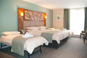 a hotel room with three beds with white sheets at Drimsynie Estate Hotel in Lochgoilhead +29 photos