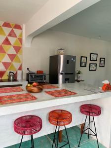 une cuisine avec un comptoir et deux tabourets rouges dans l'établissement CoCo 2 Spacious Apartment Downtown with Garden, à Cozumel