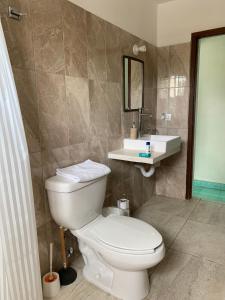 uma casa de banho com um WC branco e um lavatório. em CoCo 2 Spacious Apartment Downtown with Garden em Cozumel