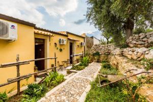 una casa amarilla con una pared de piedra en Agriturismo Monte Criscione, en Avola