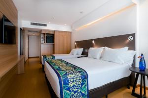 um quarto de hotel com uma cama grande e uma televisão em Arena Copacabana Hotel no Rio de Janeiro