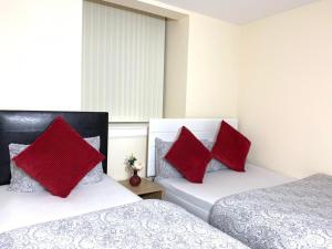 two beds with red pillows in a bedroom at Edinburgh Ocean Inn in Edinburgh