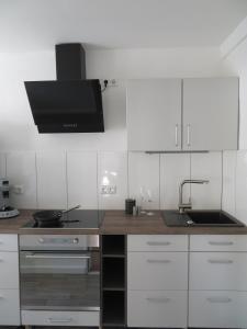 cocina con armarios blancos, fregadero y microondas en Ferienapartment Hugos en Balve