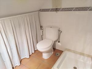 ein Badezimmer mit einem weißen WC und einer Badewanne in der Unterkunft Insua in Malpica