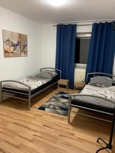 two beds in a room with blue curtains at Heinsberg City in Heinsberg