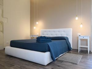 a bedroom with a white bed with a blue blanket at Masseria Case Damma in Case Monterosso