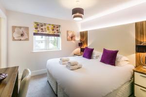 a bedroom with a large white bed with purple pillows at Golf Apartment @ Carus Green in Kendal