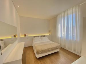 a white bedroom with a bed and a window at Soggiorno Lo Stellino in Siena