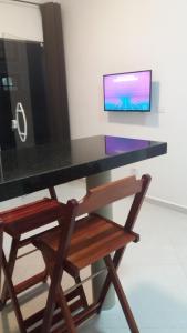 a desk with a chair and a tv on a wall at Villagio Aloha Beach in Bertioga