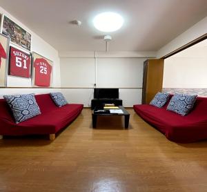 ein Wohnzimmer mit zwei roten Sofas und einem Tisch in der Unterkunft Laforet Tokaichi / Vacation STAY 75082 in Hiroshima