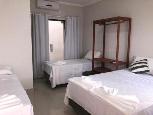 a hotel room with two beds and a mirror at Pousada Veleiro in Porto Seguro +11 photos