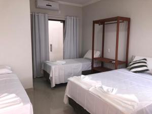 a hotel room with two beds and a mirror at Pousada Veleiro in Porto Seguro