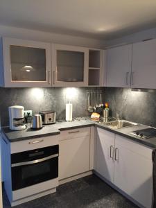eine Küche mit weißen Schränken und einer Spüle in der Unterkunft Apartment Charlotte in Zirkow + 12 Fotos