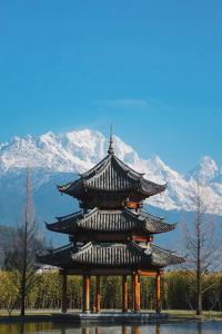 un grand bâtiment avec des montagnes enneigées en arrière-plan dans l'établissement Banyan Tree Lijiang, à Lijiang