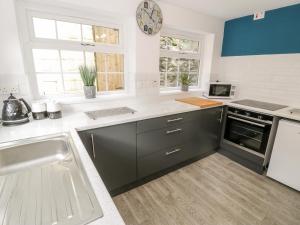 a kitchen with a sink and a clock on the wall at Encil in Caernarfon