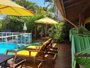a deck with chairs and an umbrella and a pool at Pousada Palhocinha Garopaba in Garopaba