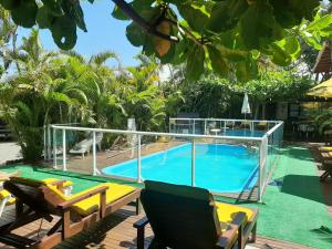 una piscina con 2 tumbonas junto a ella en Pousada Palhocinha Garopaba, en Garopaba