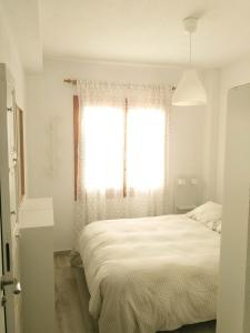 a white bedroom with a bed and a window at Apartamento Santa Pola in Santa Pola