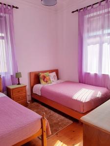 コインブラにあるFarol de Vidaのベッドルーム(ベッド2台、紫色のカーテン付)