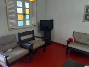 a living room with two chairs and a tv at Casa 5 quartos, ampla, a 100 metros da praia. Amigos e família são bem vindos a essa casa. Venha viver momentos inesquecíveis aqui. in Guarapari