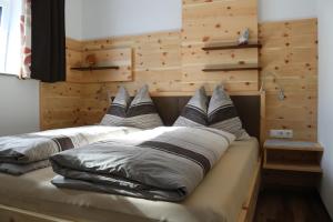 2 Kissen auf einem Bett in einem Zimmer mit Holzwänden in der Unterkunft beim Tischler in Vorderstoder