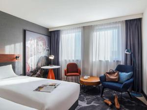 a hotel room with a bed and a desk and chairs at Mercure Amsterdam City Hotel in Amsterdam