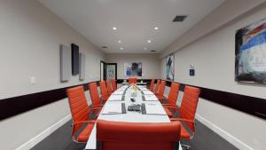 a conference room with a long table and orange chairs at Nuvo Suites Hotel - Miami Doral in Miami +76 photos