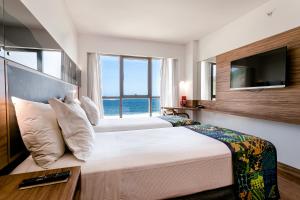 a bedroom with a large bed and a television at Arena Leme Hotel in Rio de Janeiro