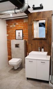 ein Badezimmer mit einem weißen Waschbecken und einem WC in der Unterkunft RedCity LOFT in Żyrardów