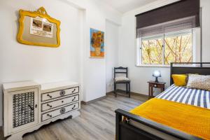 a bedroom with a bed and a dresser and a window at Kwadalayo Art Quarters in Faro