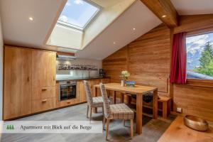 eine Küche mit einem Tisch, Stühlen und einem Dachfenster in der Unterkunft Hotel Waldrand in Lenk im Simmental