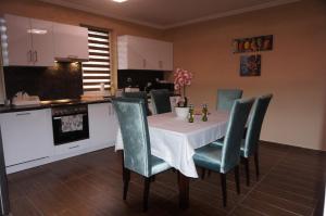 a kitchen with a table with green chairs and a kitchen at Toscana 3 Debrecen in Debrecen