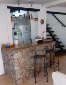 a kitchen with a stone counter and stools in a room at Casa de Campo de Familiar in Tafí del Valle