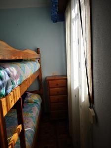 a bedroom with a bunk bed and a dresser and a window at La Casina in Sevares