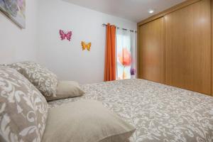 1 dormitorio con 1 cama con mariposas en la pared en vicino al porto confortevole Wi-Fi en Morro del Jable